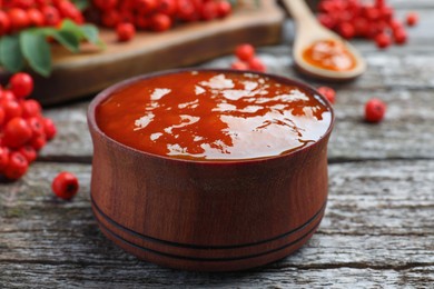 Photo of Delicious rowan jam in bowl on wooden table, closeup