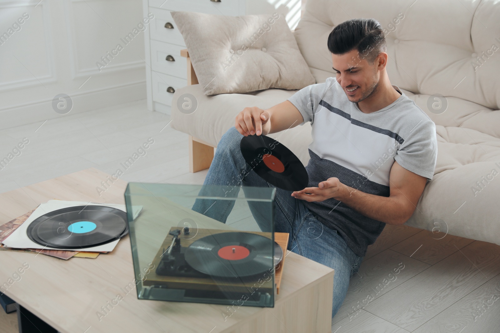 Photo of Happy man listening to music with turntable at home