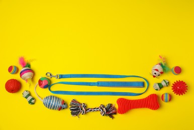 Flat lay composition with pet leash and toys on yellow background, space for text