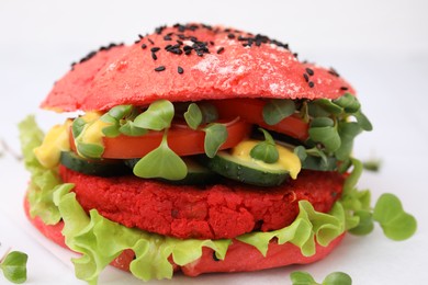 Photo of Tasty pink vegan burger with vegetables, patty and microgreens on white background, closeup