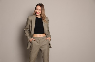 Photo of Portrait of beautiful young woman in fashionable suit on grey background, space for text. Business attire