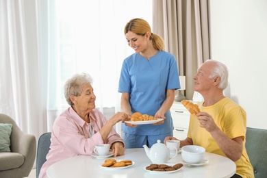 Nurse assisting while elderly people having breakfast at retirement home