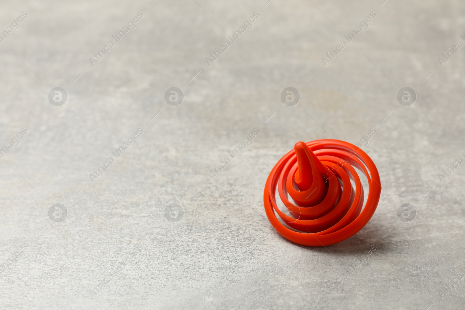 Photo of Red spinning top on grey textured background, closeup. Space for text