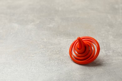 Red spinning top on grey textured background, closeup. Space for text