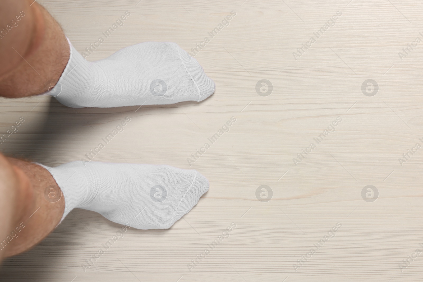 Photo of Man in stylish socks standing on white wooden floor, top view. Space for text