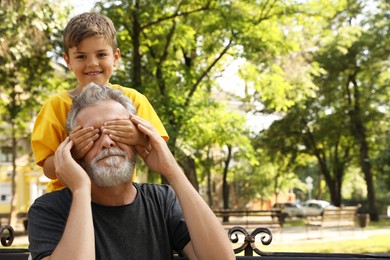 Senior man with his little grandson having fun together in park