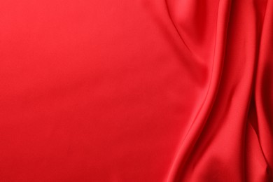 Crumpled red silk fabric as background, top view. Space for text