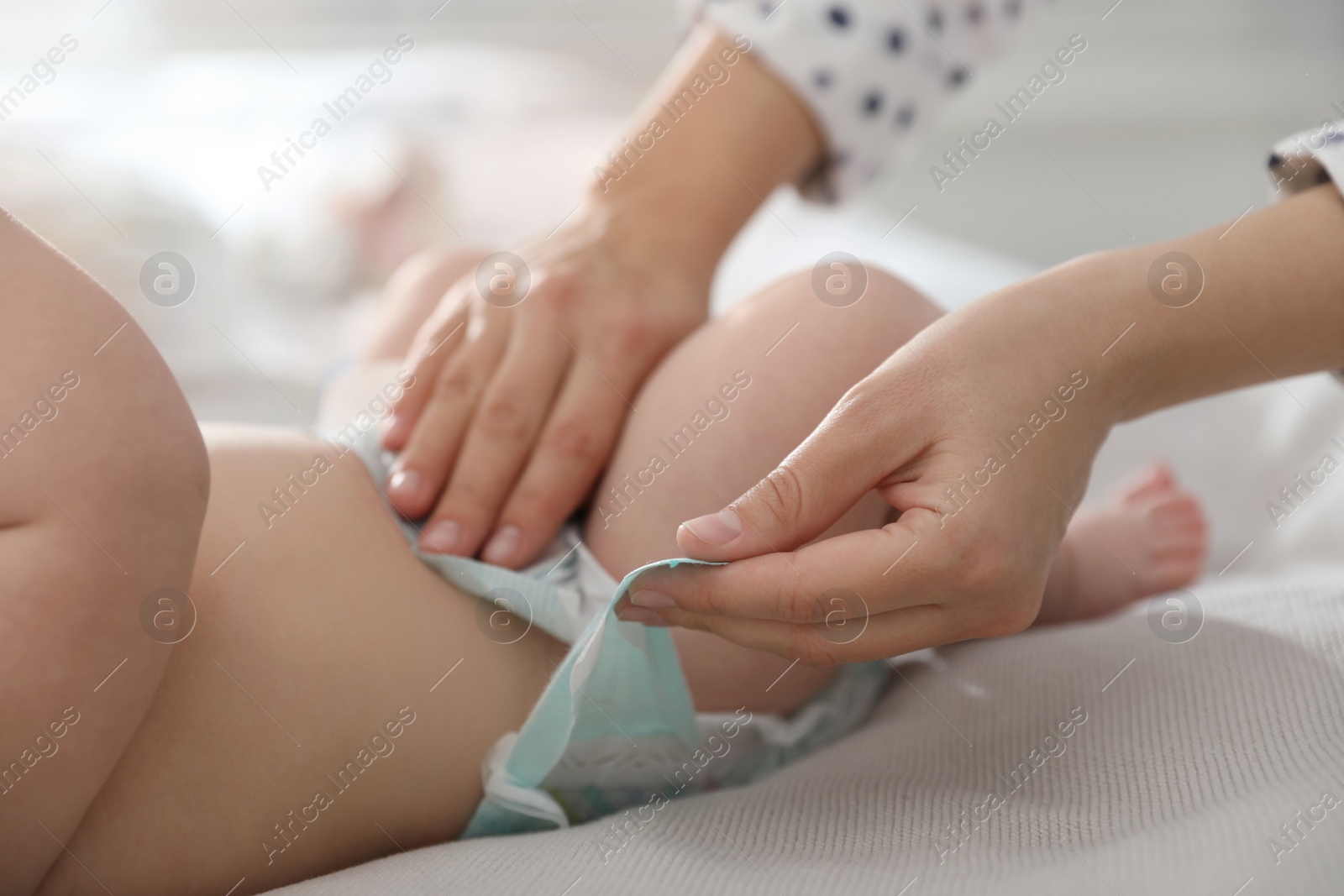 Photo of Mother changing her baby's diaper on bed, closeup