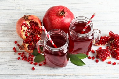 Mason jars of pomegranate juice and fresh fruits on wooden background