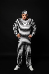 Prisoner in striped uniform on black background