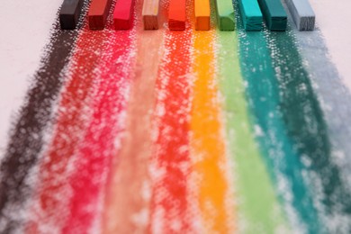 Photo of Colorful pastel chalks on white background, closeup. Drawing materials