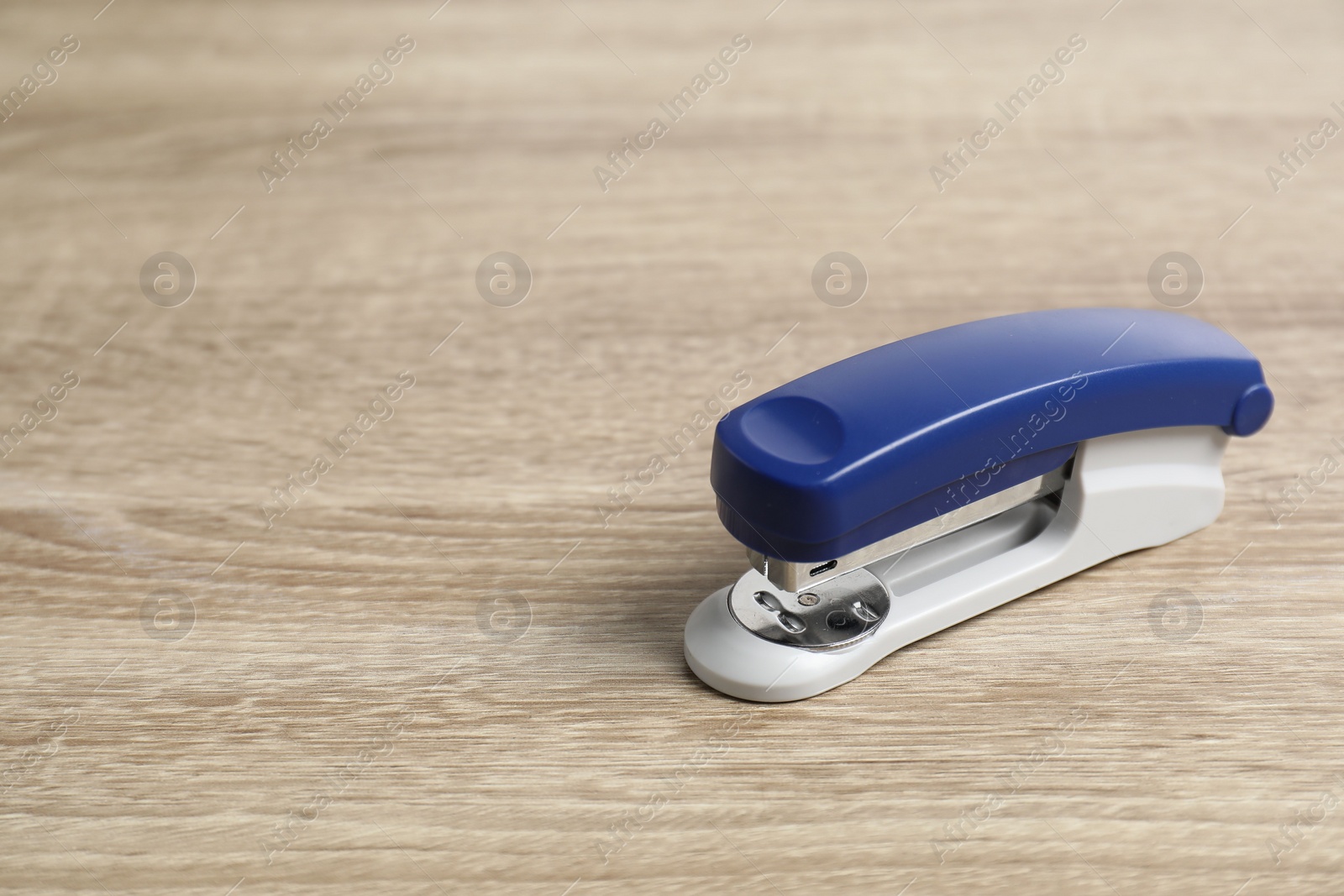 Photo of Bright stapler on wooden table, closeup. Space for text