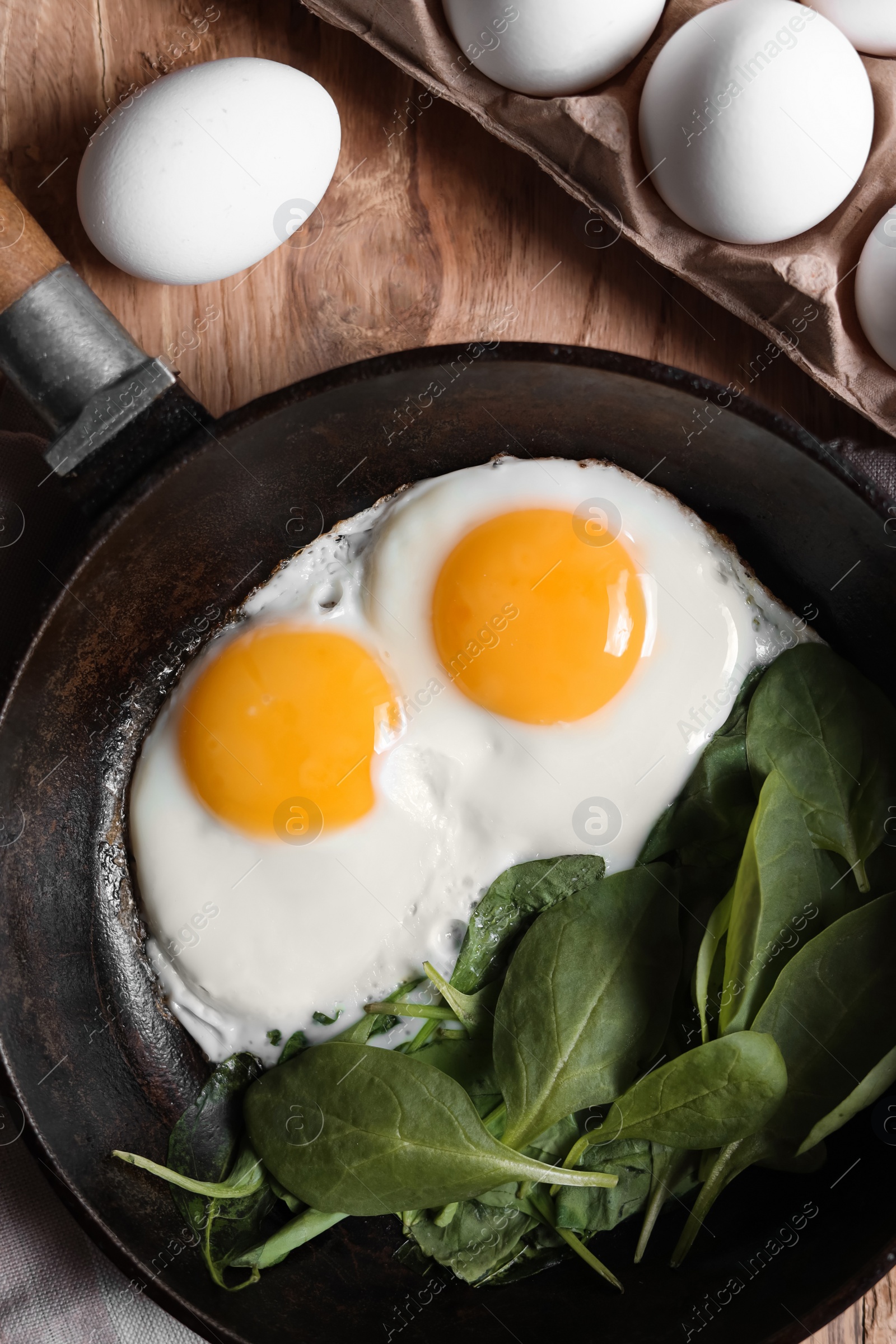 Photo of Delicious fried egg with spinach served on wooden table, flat lay