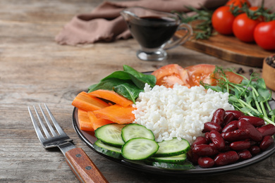 Photo of Tasty rice with beans and vegetables on wooden table, closeup