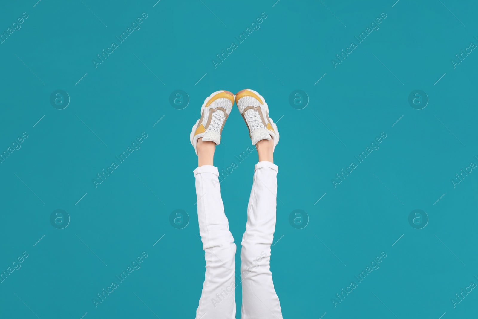 Photo of Woman in stylish sport shoes on light blue background