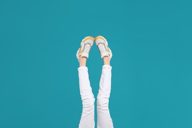 Photo of Woman in stylish sport shoes on light blue background