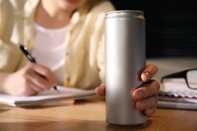 Photo of Young woman with energy drink studying at home, closeup
