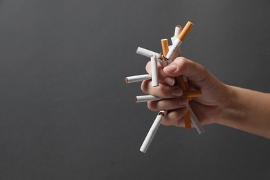 Photo of Stop smoking. Woman holding broken cigarettes on grey background, closeup. Space for text