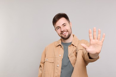 Photo of Man giving high five on grey background. Space for text