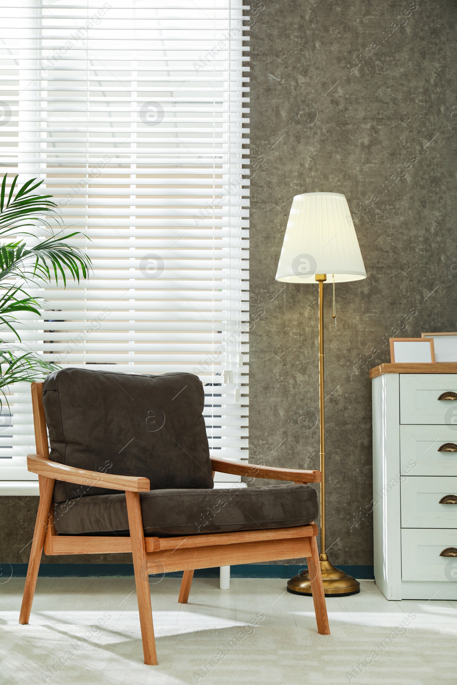 Photo of Stylish room interior with comfortable armchair and floor lamp near window