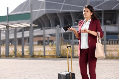 Being late. Worried businesswoman with black suitcase and passport outdoors, space for text