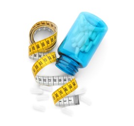 Jar of weight loss pills and measuring tape on white background, top view