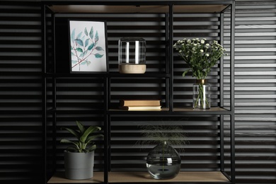 Photo of Decorative vases with plants on shelving unit indoors