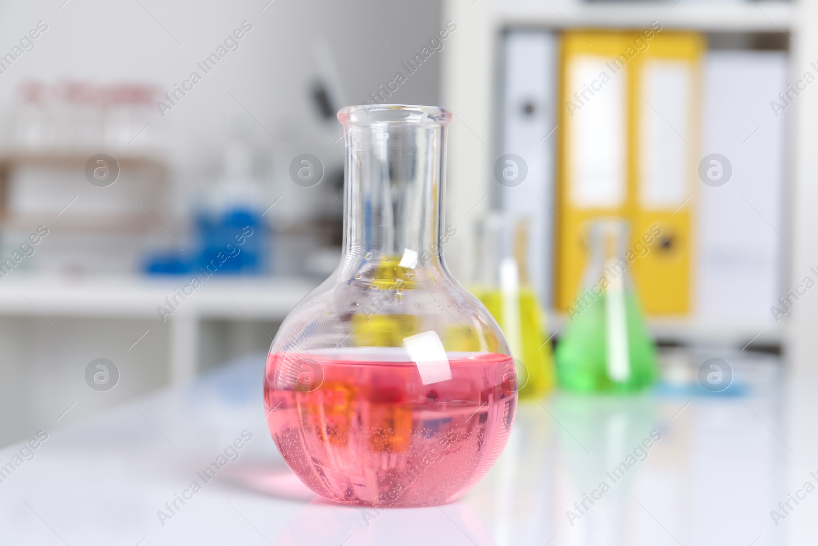 Photo of Laboratory analysis. Flask with pink liquid on white table