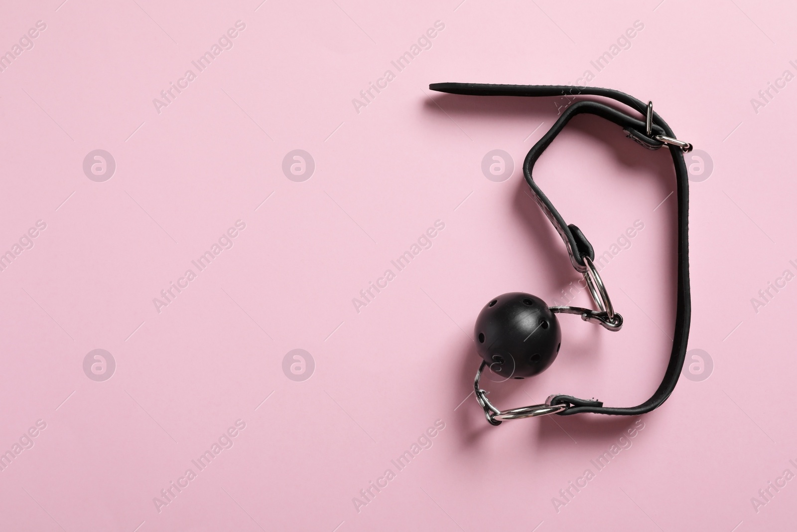 Photo of Black ball gag on pink background, top view with space for text. Sex toy