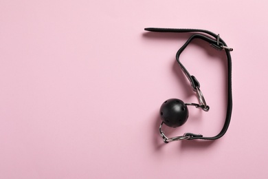 Black ball gag on pink background, top view with space for text. Sex toy