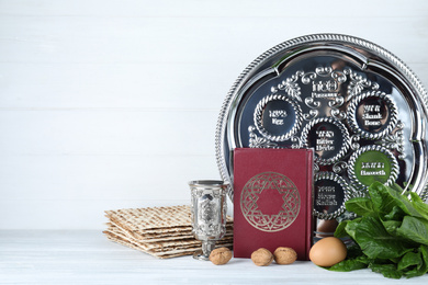Photo of Symbolic Pesach (Passover Seder) items on white wooden table. Space for text