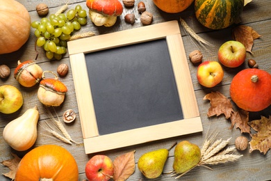 Chalkboard with space for text, autumn fruits and vegetables on wooden background, flat lay. Happy Thanksgiving day