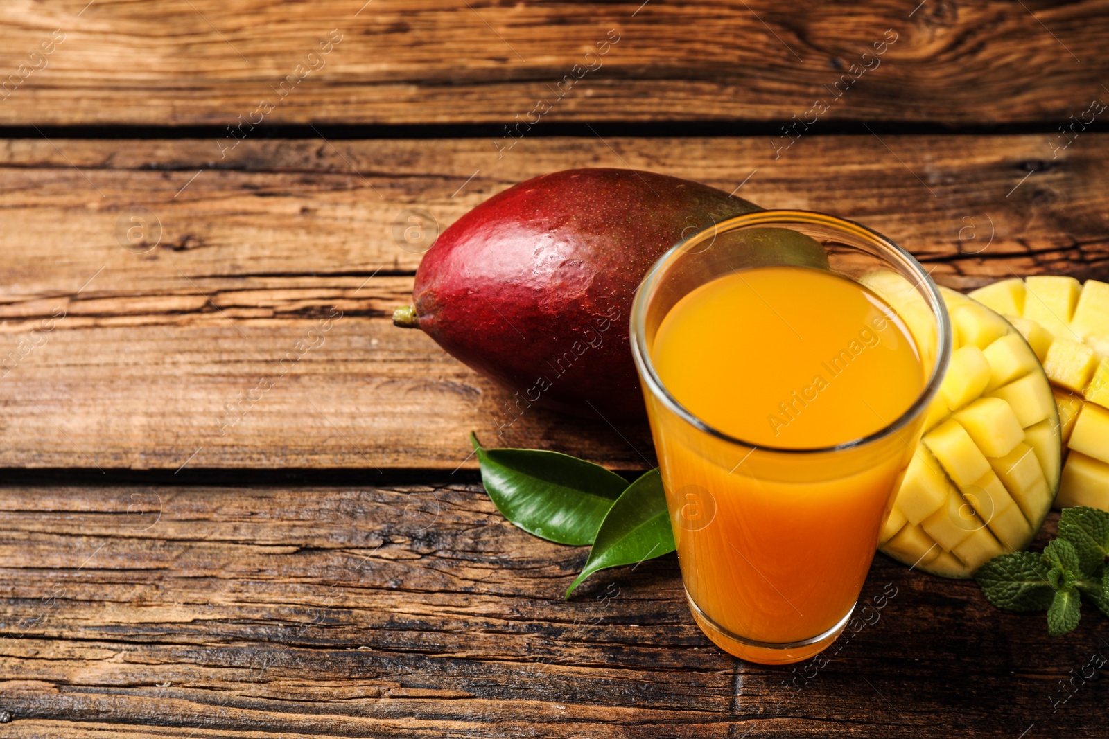 Photo of Fresh delicious mango drink on wooden table. Space for text