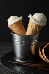 Ice cream scoops in wafer cones on gray textured table against dark background