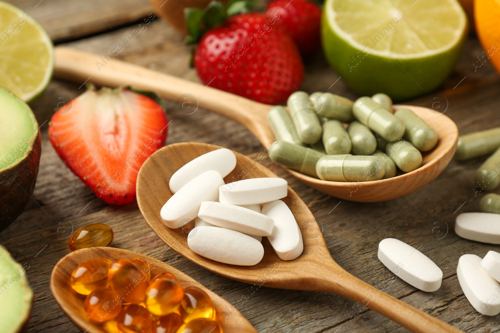 Photo of Different vitamin pills and fresh fruits on old wooden table, closeup