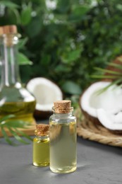 Photo of Bottles of organic coconut cooking oil and fresh fruits on grey table