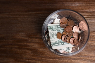 Photo of Donation jar with money on wooden background, top view. Space for text