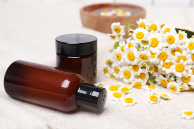 Composition with chamomile flowers and cosmetic products on table, closeup