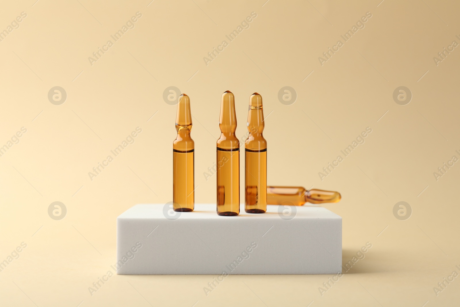 Photo of Glass ampoules with liquid on beige background