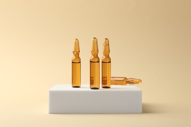 Photo of Glass ampoules with liquid on beige background