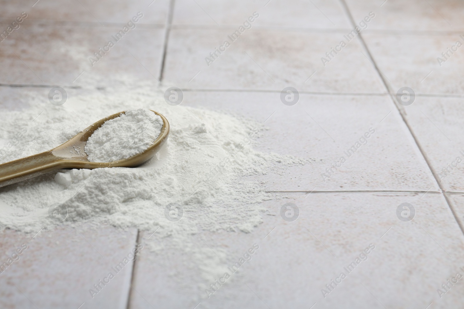 Photo of Pile of baking powder and spoon on light tiled table, closeup. Space for text