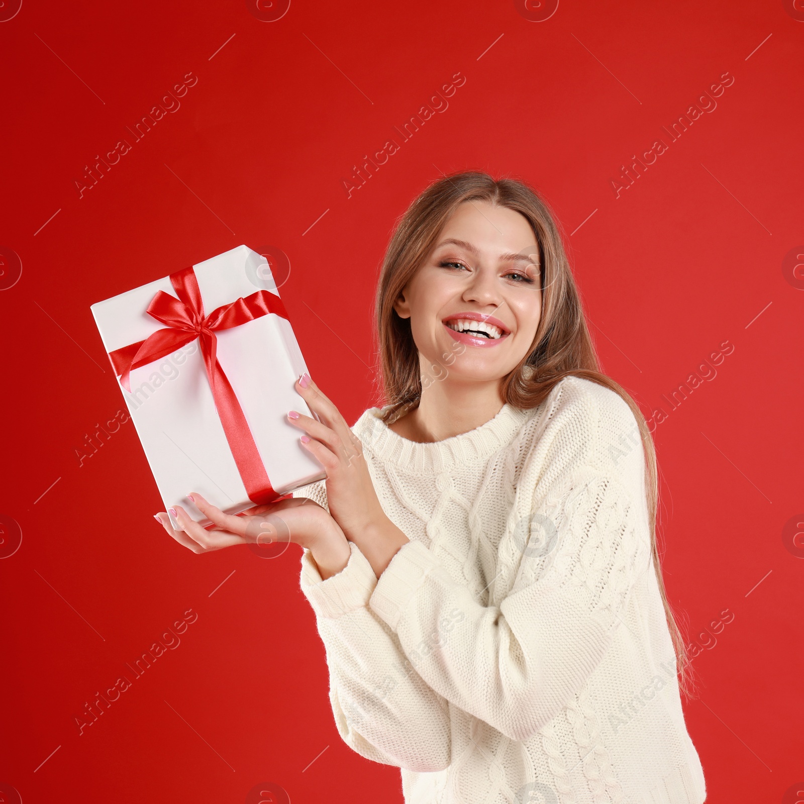 Photo of Happy young woman with Christmas gift on red background