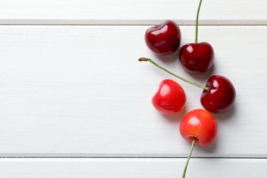 Photo of Sweet red cherries on white wooden table, flat lay. Space for text