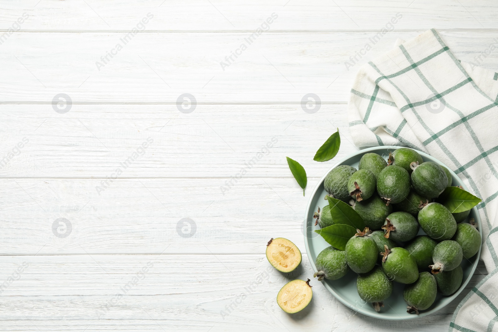 Photo of Flat lay composition with fresh green feijoa fruits on white wooden table, space for text