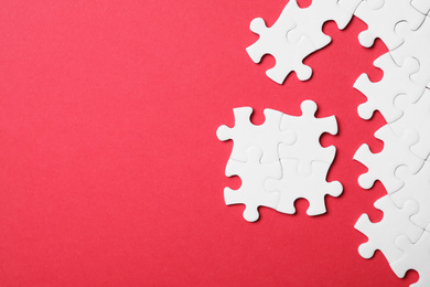 Photo of Blank white puzzle pieces on red background, flat lay. Space for text