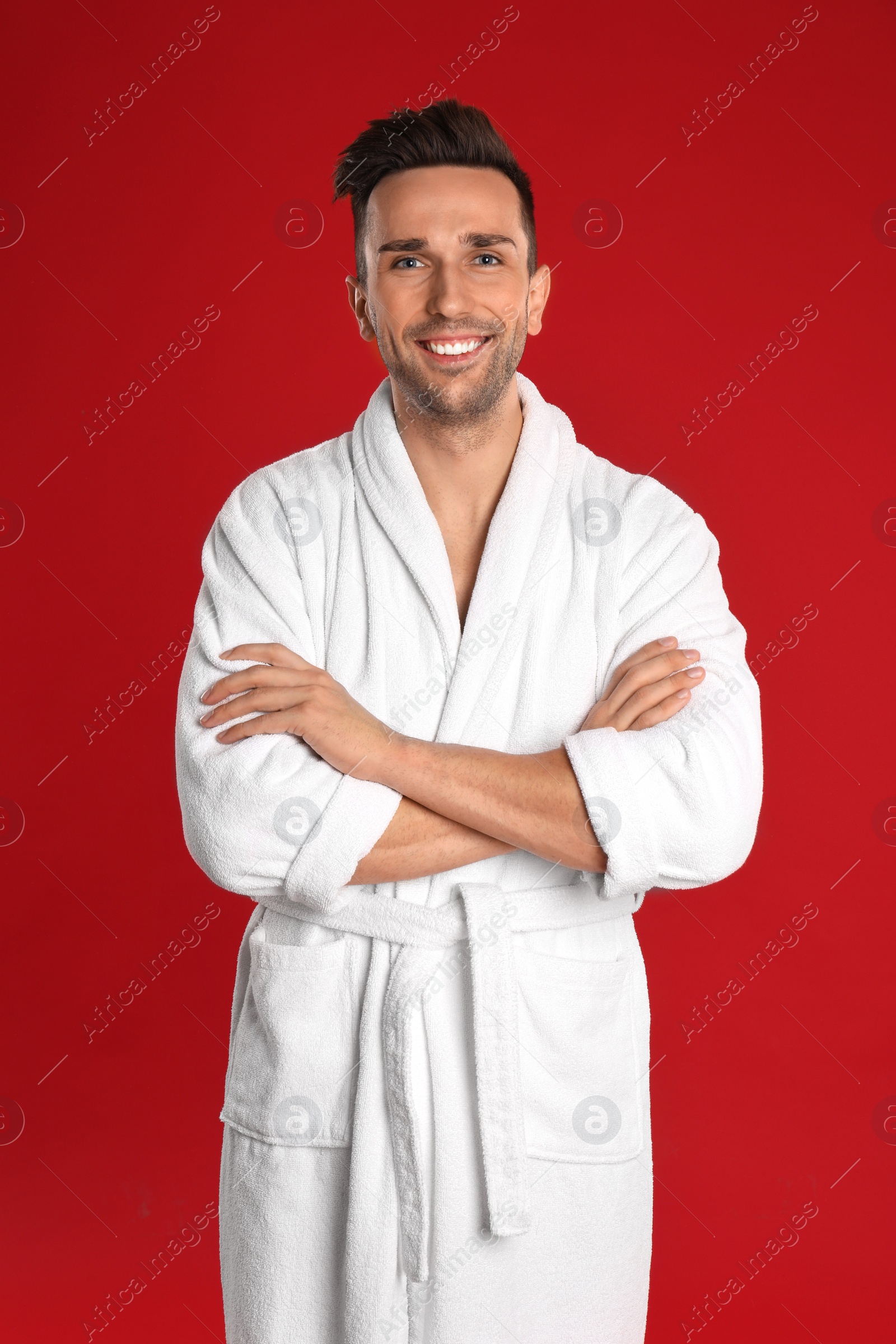 Photo of Happy young man in bathrobe on red background