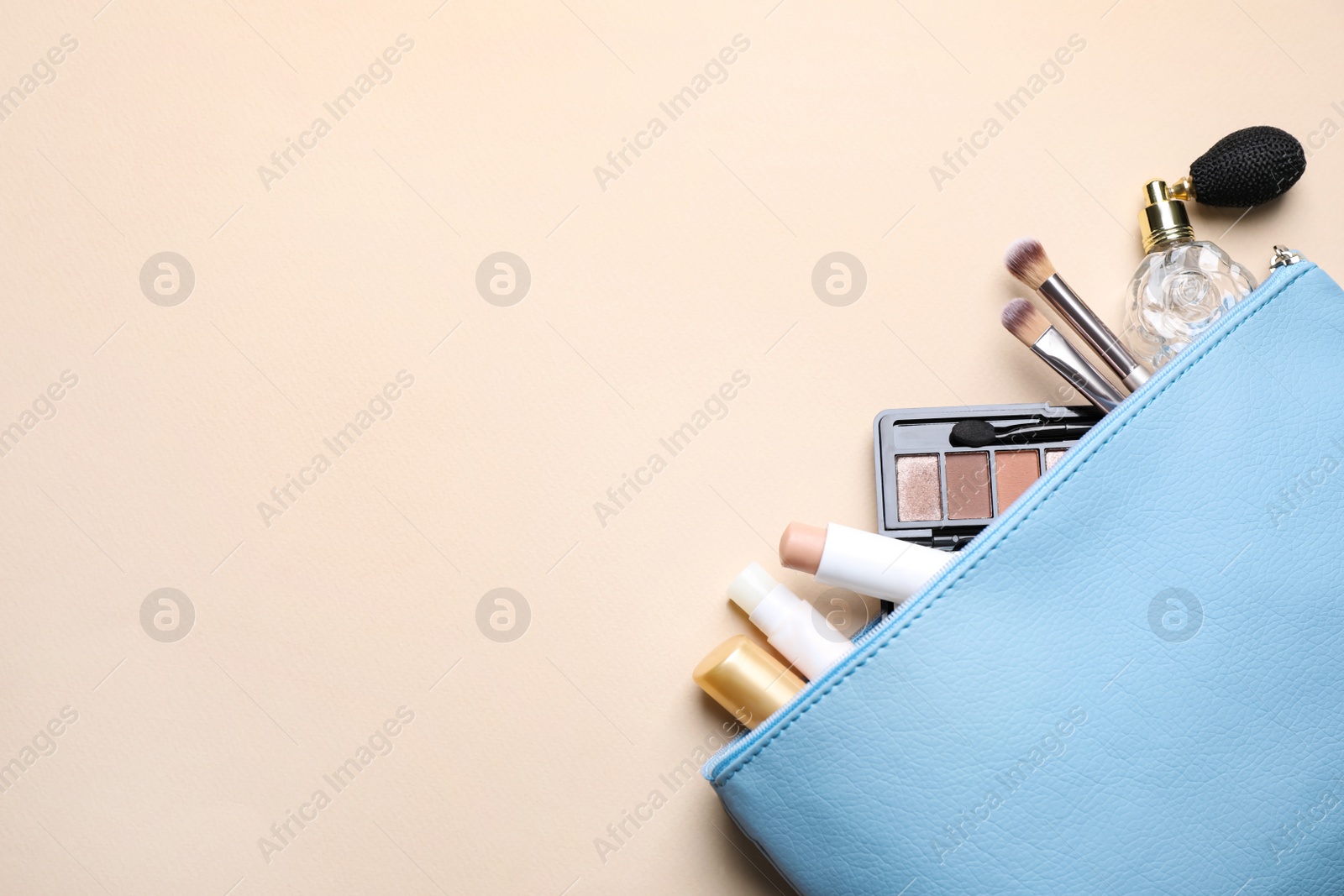 Photo of Bag with hygienic lipsticks and cosmetic products on beige background, flat lay. Space for text