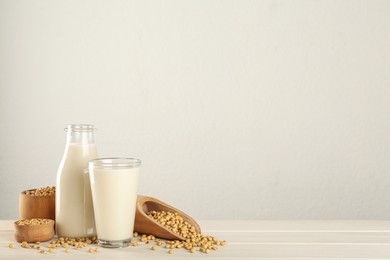 Photo of Fresh soy milk and grains on white wooden table. Space for text