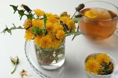 Beautiful dandelion bouquet and delicious fresh tea on white table