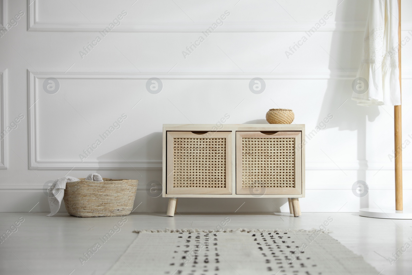 Photo of Wooden commode near white wall in room. Interior design